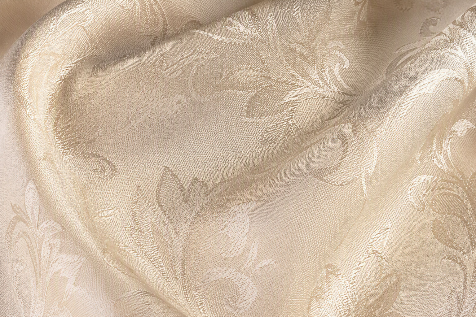Close-up of ivory damask napkin fabric showing an elegant woven satin floral pattern with subtle sheen