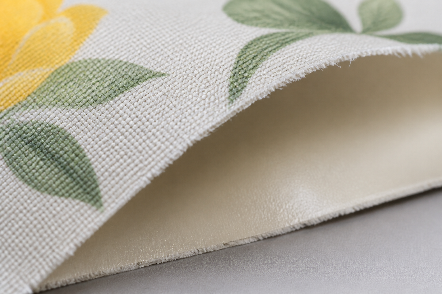 Macro view showing the layered structure of a coated tablecloth with printed face and smooth wipeable backing