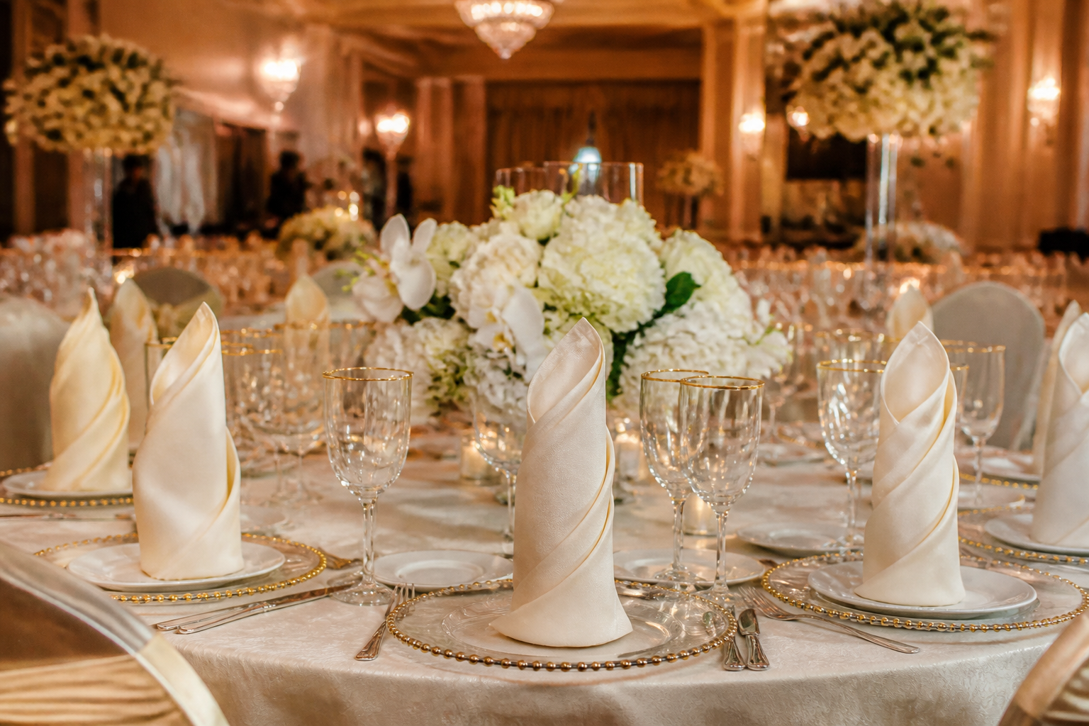 Wedding banquet table with large ivory napkins in tall elegant folds at each place setting