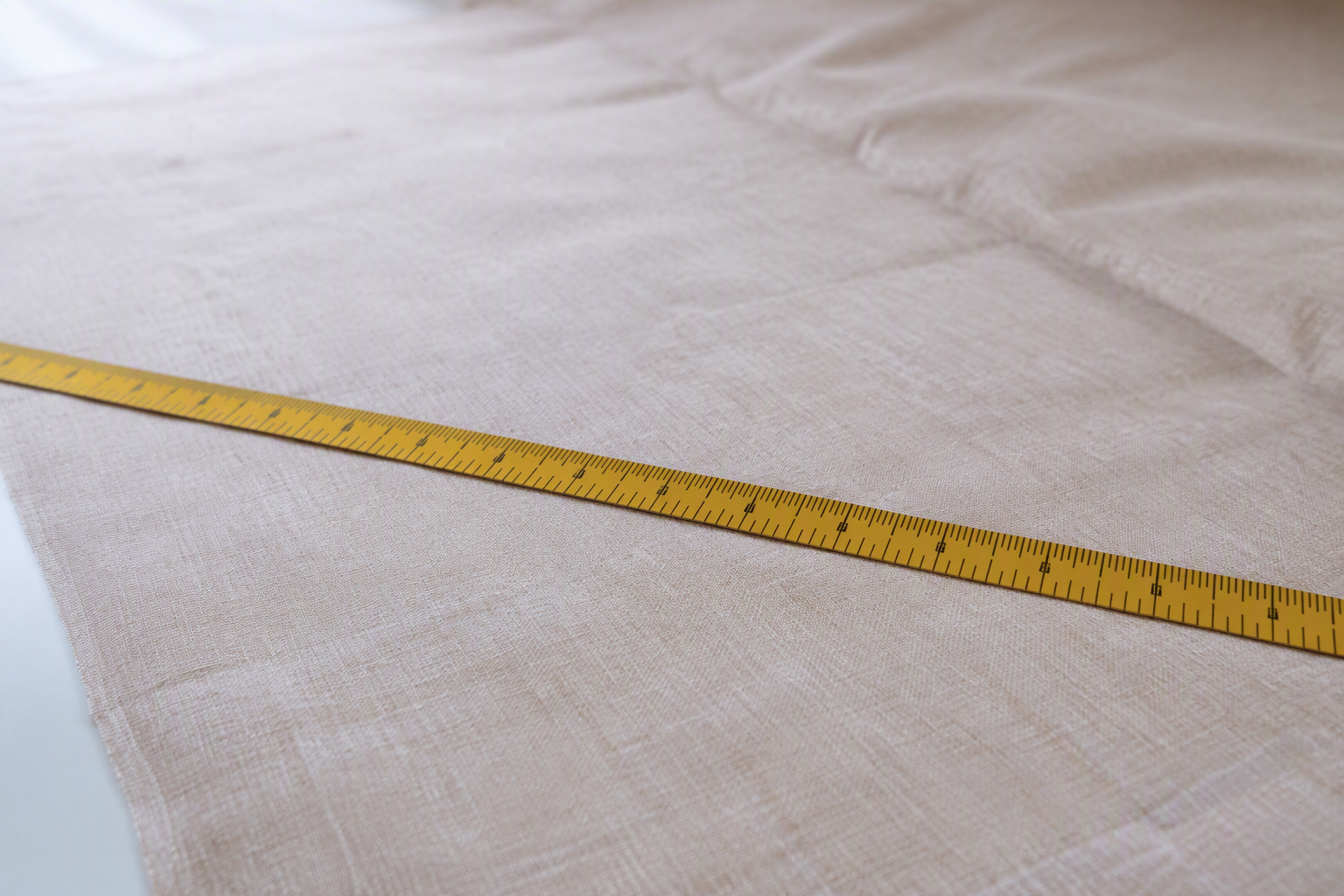 Measuring tape laid across a spread linen tablecloth on an inspection table