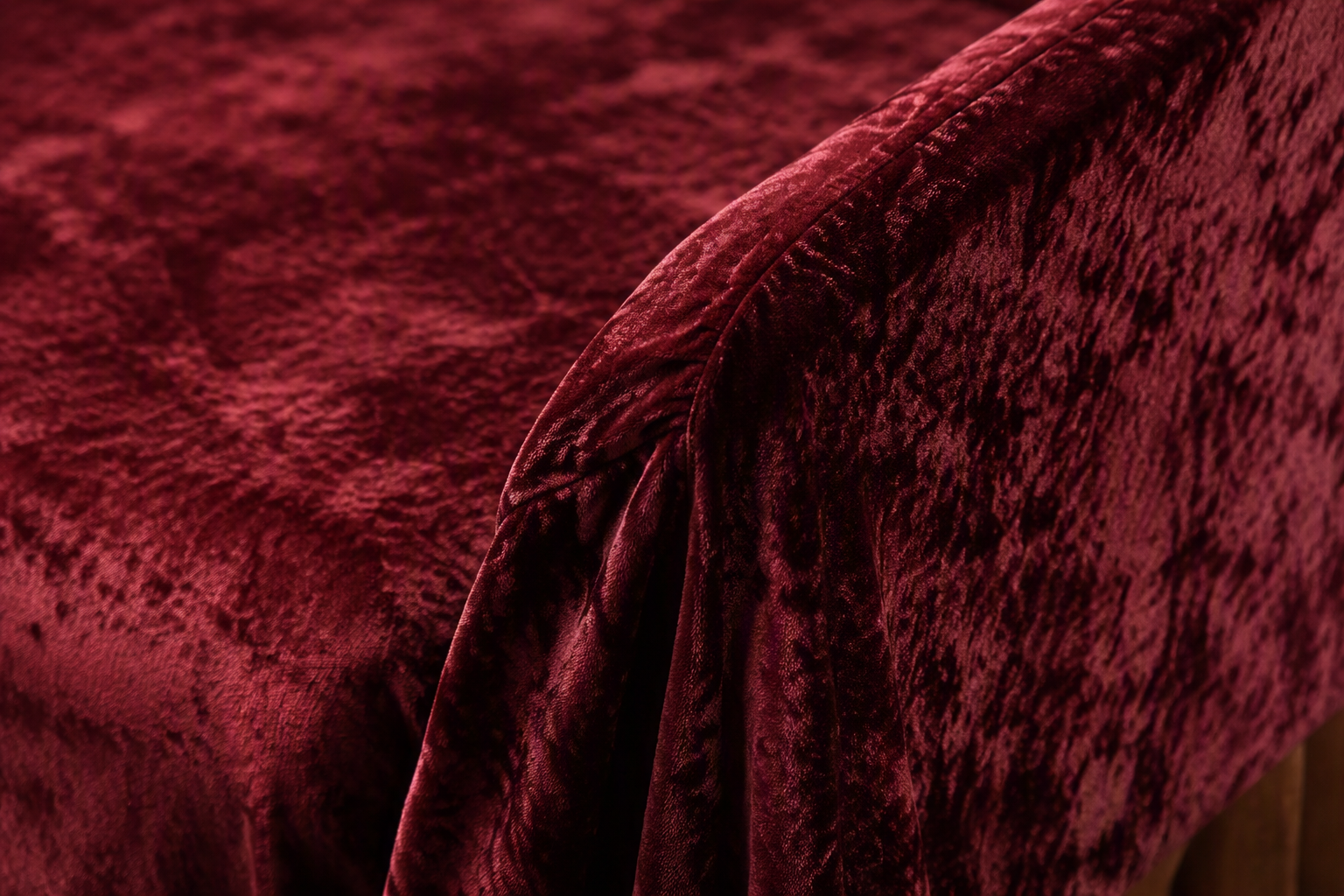 Crushed velvet chair cover fabric in deep burgundy with plush nap texture over a chair edge