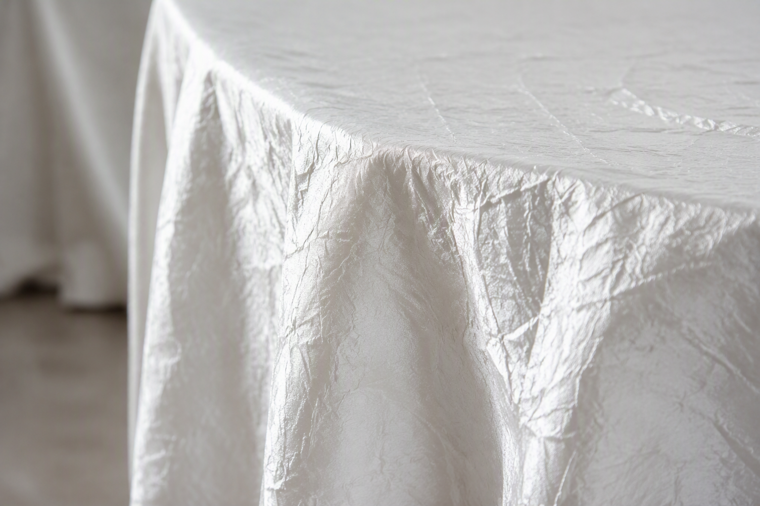 White wrinkled taffeta tablecloth draping over the edge of a table