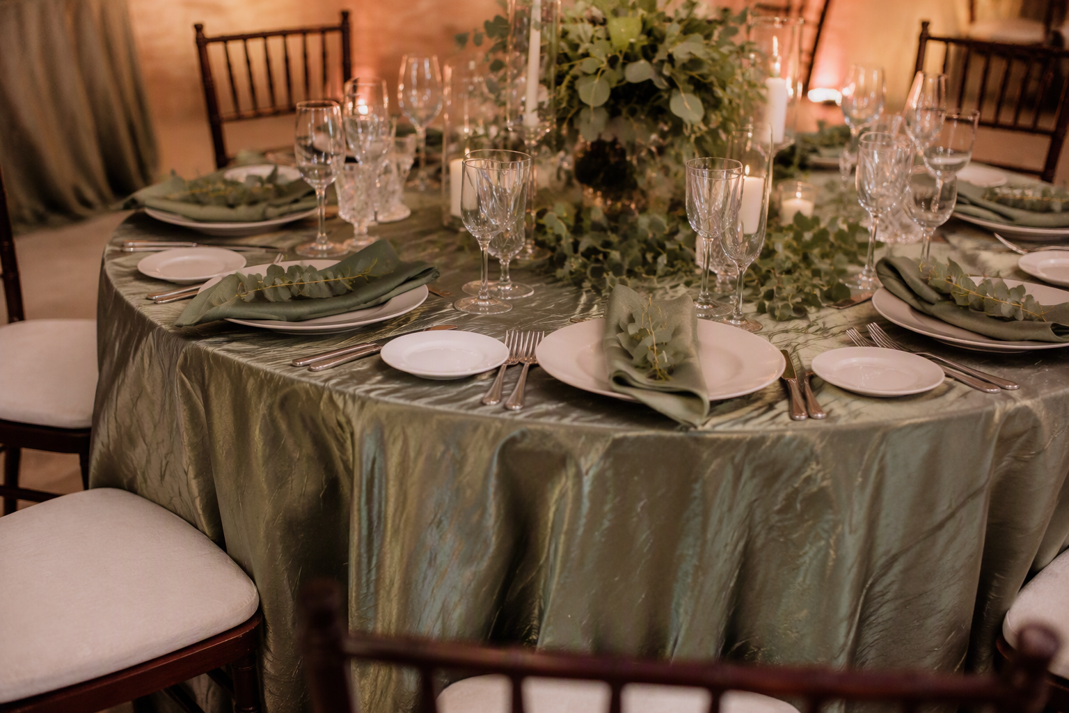 Wedding reception table styled with a deep sage green wrinkled taffeta tablecloth