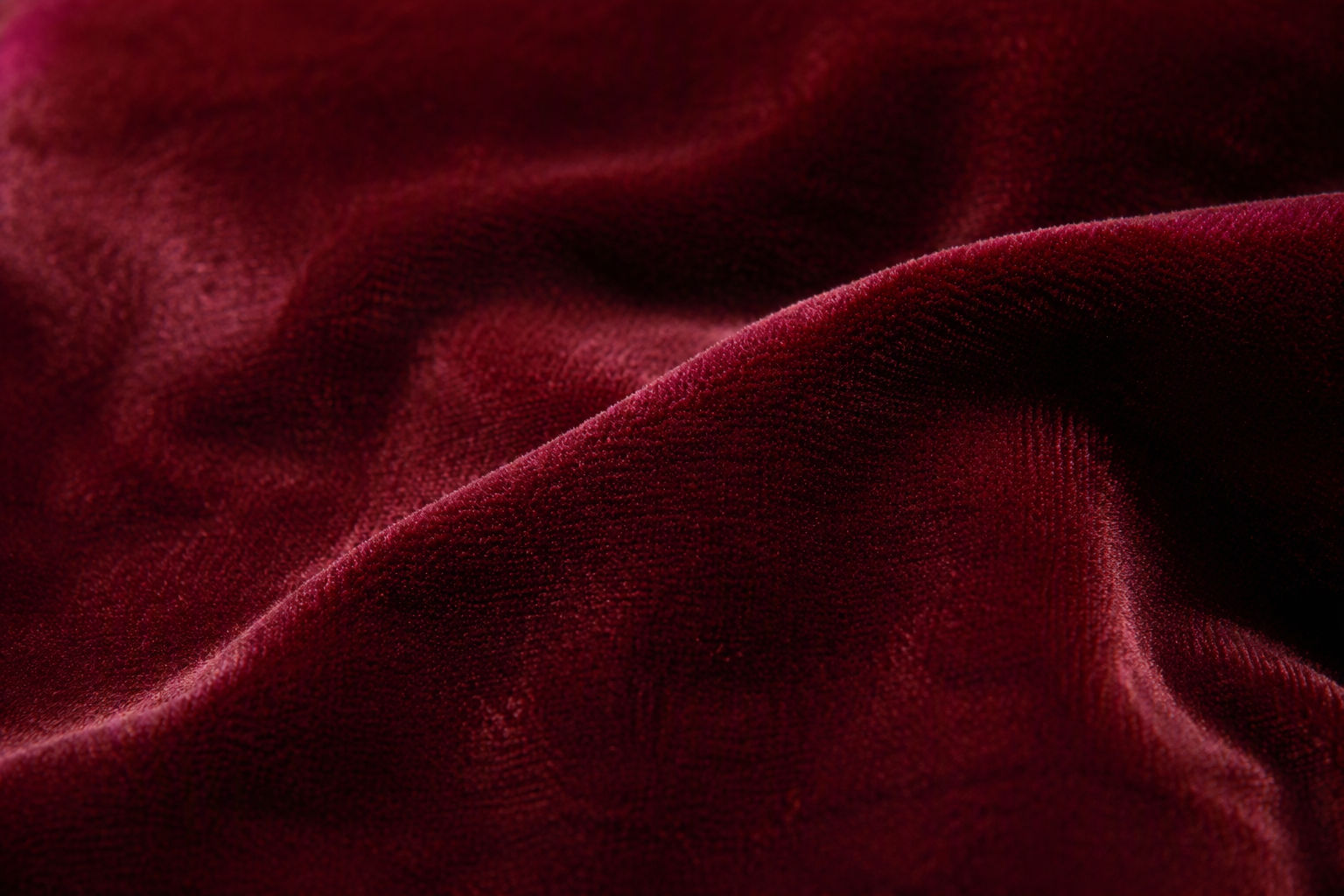 Macro close-up of deep burgundy velvet fabric showing the dense plush nap