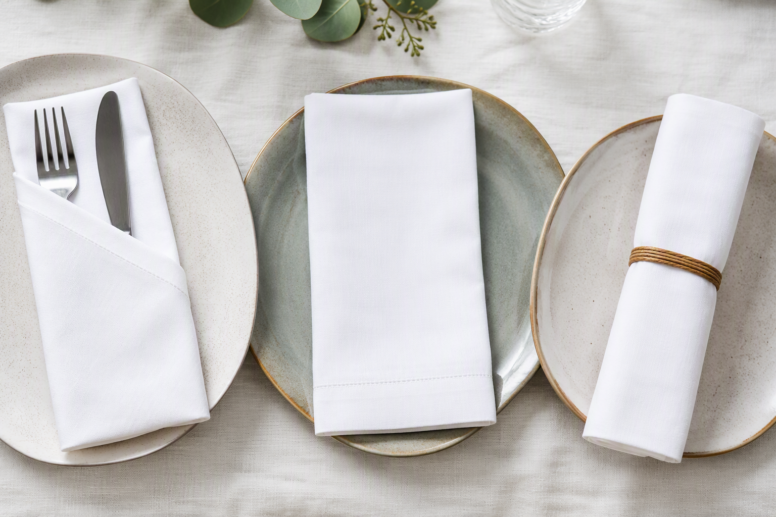 Three cotton napkins in different folds on plates, a pocket fold, a flat fold and a rolled fold
