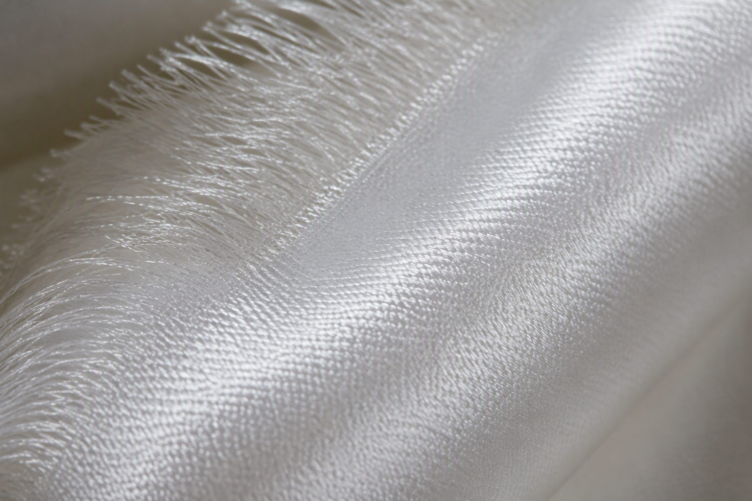 A macro close-up of white satin fabric, the smooth lustrous face catching a soft band of light
