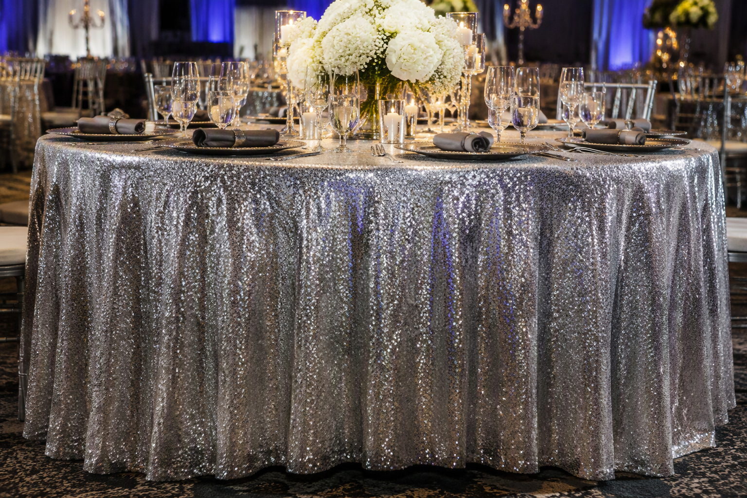 A round banquet table with a silver sequin tablecloth glittering in soft folds