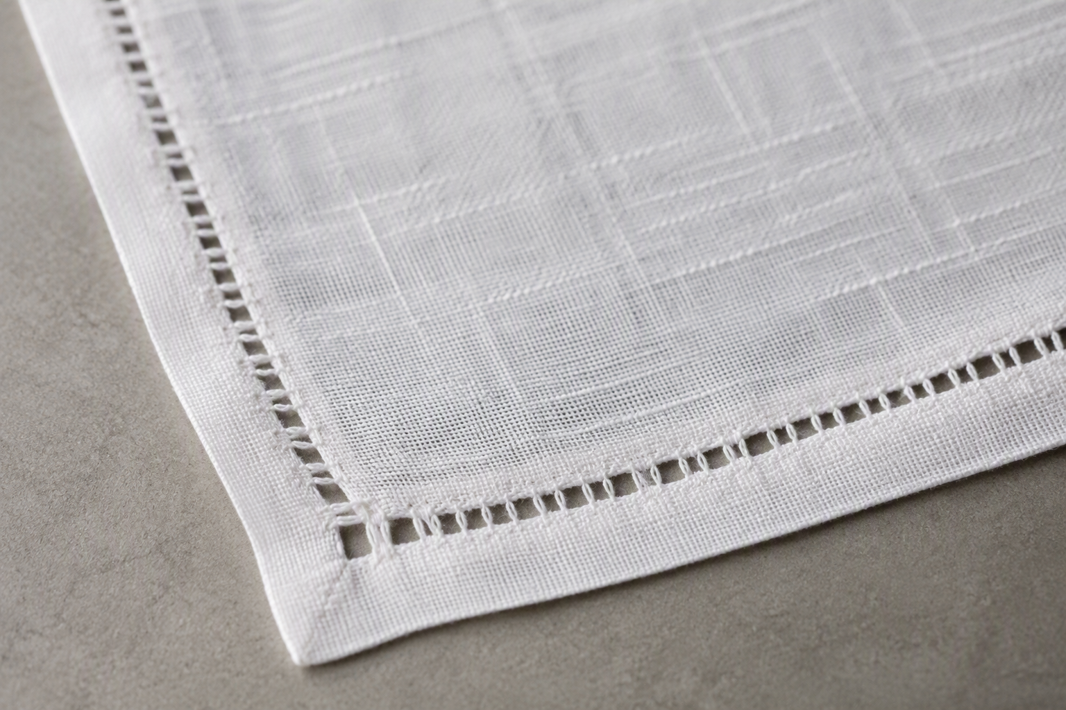 The hemstitched openwork edge of a white linen napkin