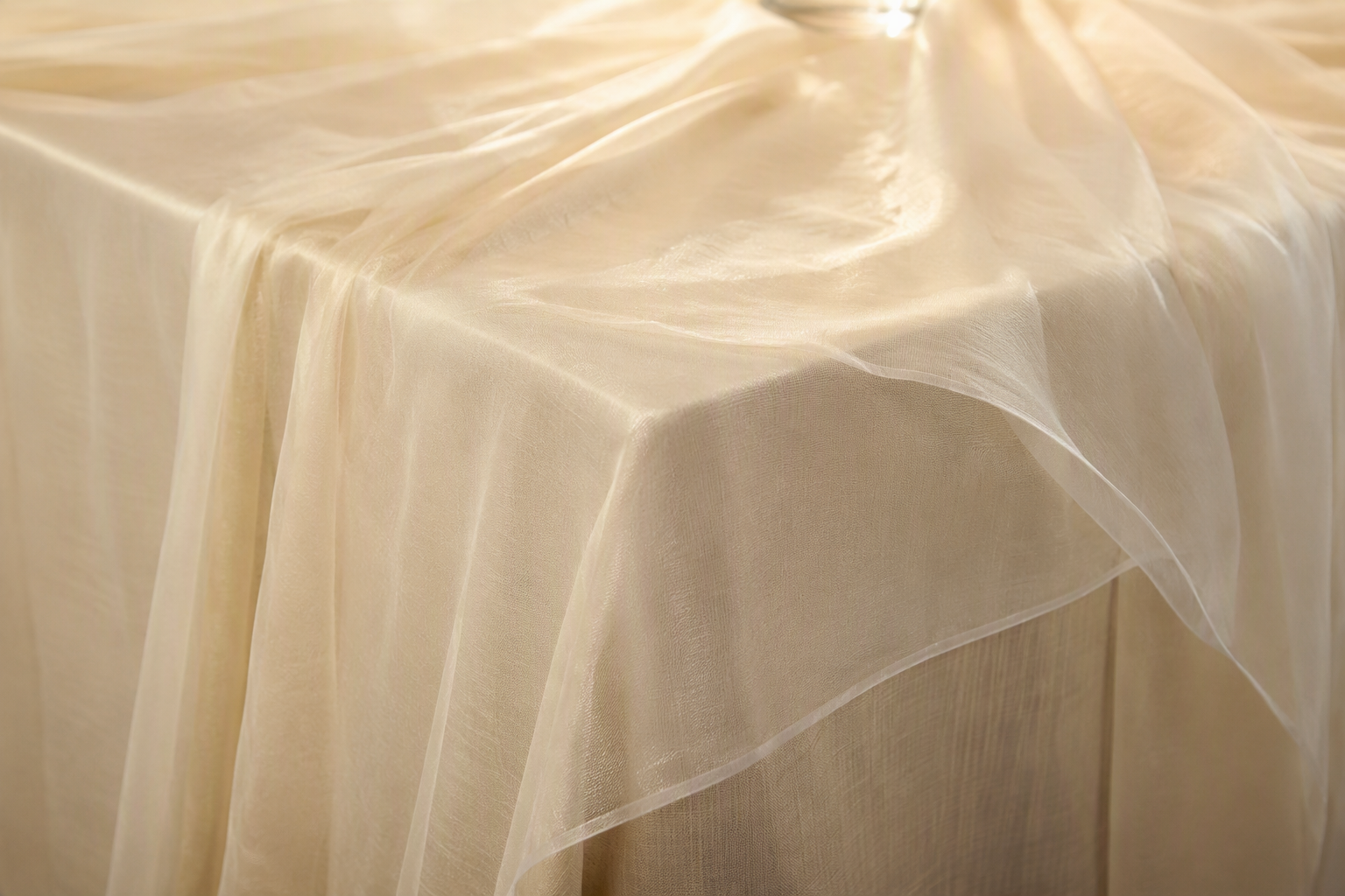 A sheer chiffon overlay layered over an ivory under-layer tablecloth